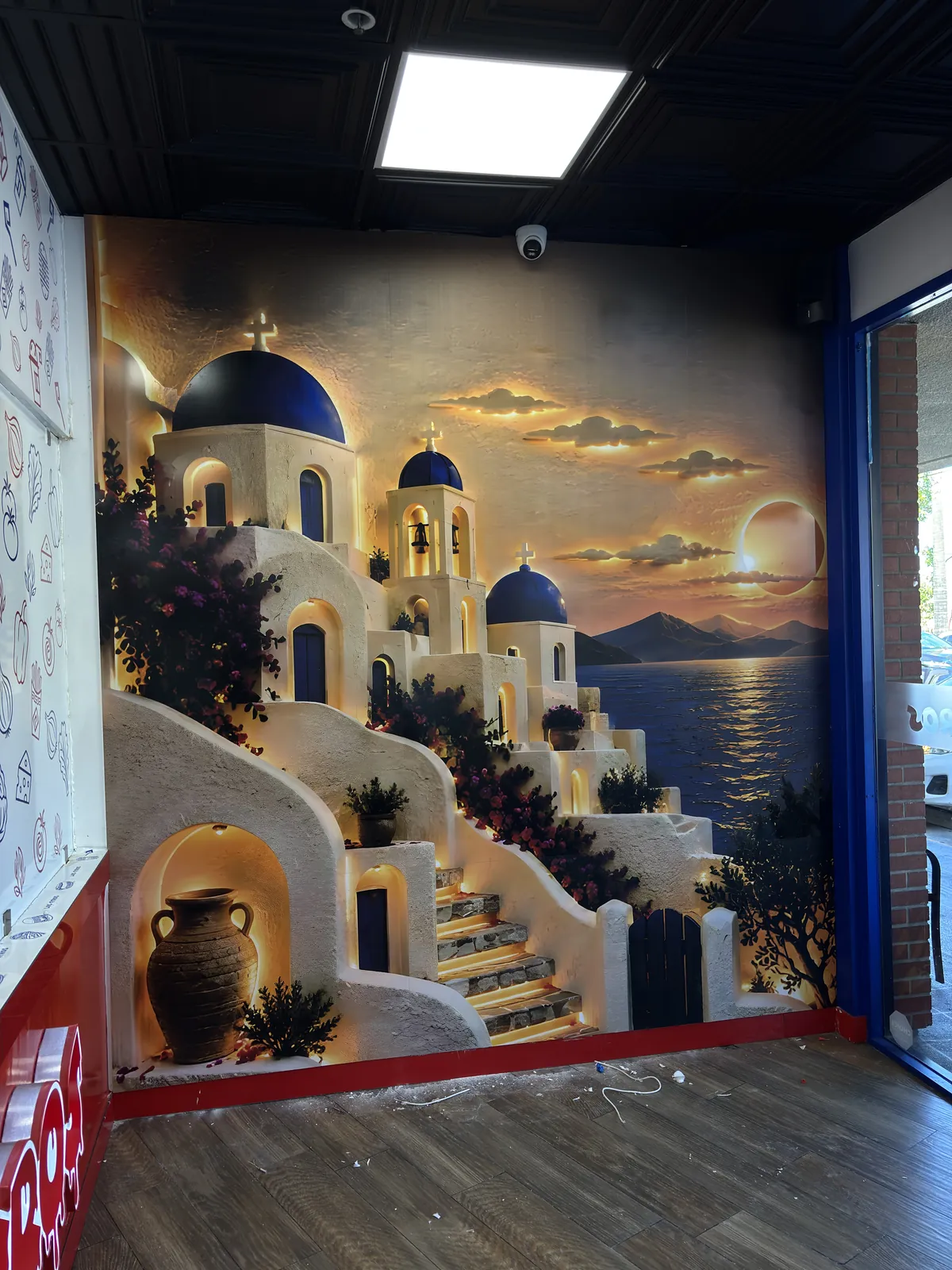 A 9 by 9 foot raised UV wall panel of a Santorini scene on a restaurant wall